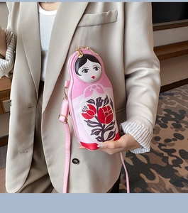 Detailed close-up of a pink Russian doll crossbody bag with floral pattern and slim strap