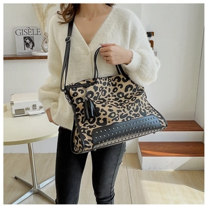 Dettaglio della borsa tote leopardata con nappa nera e borchie indossata dal modello