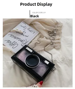 Detail of black camera-shaped crossbody bag with polished mirror finish and silver chain