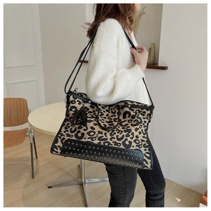 Dettaglio della borsa tote leopardata con borchie metalliche e ciondolo a frange