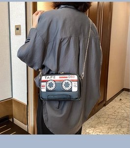 Close-up of retro tape recorder crossbody bag with gold chain strap on a model