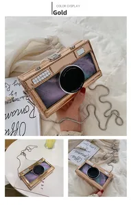 Detail of camera-shaped gold crossbody bag with clear window and colorful feathers