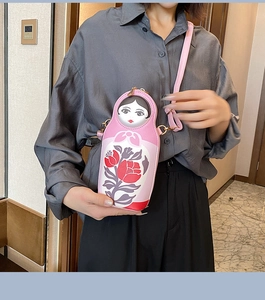 Pink Russian doll crossbody bag with floral patterns worn by a model on a shoulder strap