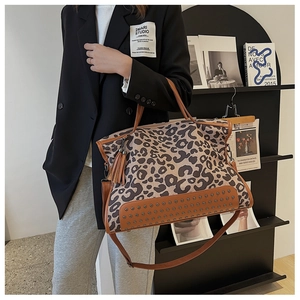 Vista dettagliata della borsa tote leopardata con borchie metalliche e nappe marroni
