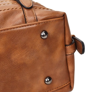 Detailed macro view of the brown leather bag base with protective metal feet and stitching