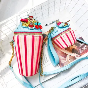 Close-up of pink cupcake-shaped shoulder bag with cherry detail and blue chain strap