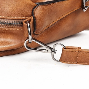 Close-up of caramel brown leather bag with gunmetal grey zippers and fine stitching