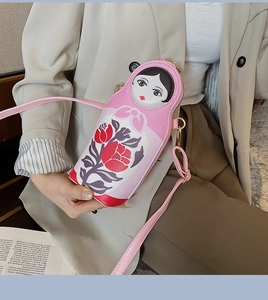 Detail of pink Russian doll crossbody bag with floral patterns on beige suit outfit
