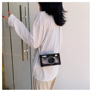Detail of creative camera-shaped crossbody bag with glossy finish and metal chain strap