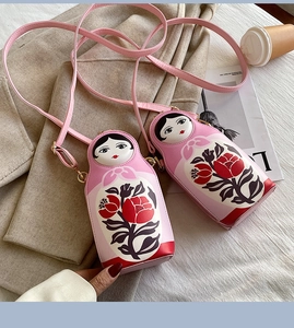 Detail of pink Russian nesting doll crossbody bag with floral pattern on leather