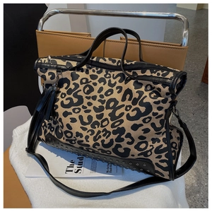 Dettaglio della borsa tote leopardata con finiture in pelle nera e borchie sul fondo