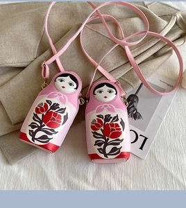 Detail of pink Russian doll cross-body bags with red floral patterns on soft fabric