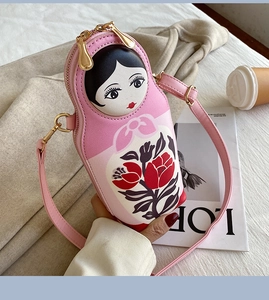 Close-up of pink Russian nesting doll crossbody bag with floral pattern and gold zipper
