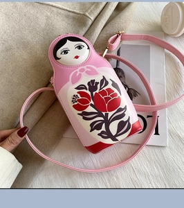 Detailed view of pink matryoshka PU leather crossbody bag on a stylish wool coat background