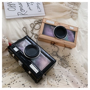 Close-up of camera-shaped bag featuring purple feather decor and silver chain strap