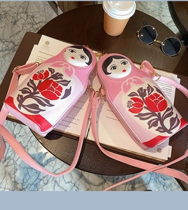Detailed view of pink Russian nesting doll crossbody bags on a vintage wooden table