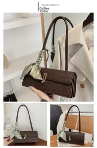 Close-up of coffee brown crocodile-embossed shoulder bag with gold clasp and silk scarf