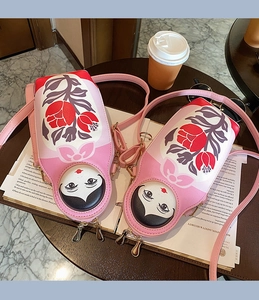 Detail of Russian doll crossbody bag with dual zipper closure and floral pattern