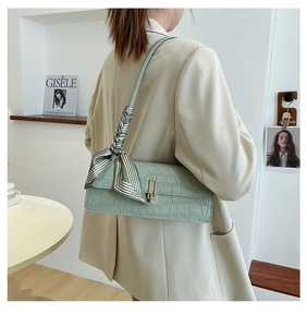 Detail of light green stone texture leather bag with striped scarf and metal buckle