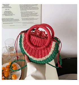 Detail of watermelon straw handbag showing woven texture and red round handles