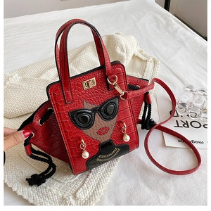 Detail of red crocodile texture handbag with cartoon figure and pearl earring accents