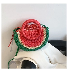 Detailed view of handmade watermelon straw bag with green handle and drawstring closure
