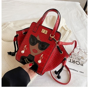 Detail of red croc-embossed handbag with art portrait patch and gold twist-lock