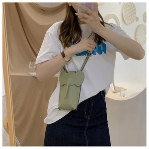 Mirror selfie showing a grass green elephant-shaped mini leather crossbody phone bag