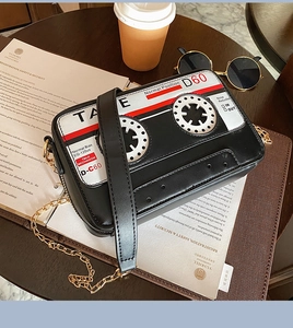 Retro cassette tape crossbody bag with gold chain strap on a wooden table setup