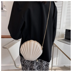 Detail view of pearlized white shell crossbody bag with gold chain and pearl zipper charm
