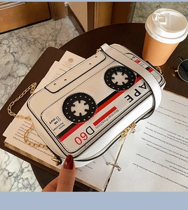 Close-up of retro cassette tape shaped shoulder bag with golden chain on a wooden desk