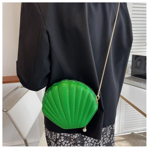 Detail of green shell crossbody bag with leather texture and pearl zipper charm