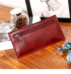 Detalle de una cartera retro de cuero encerado color granate sobre una mesa de madera