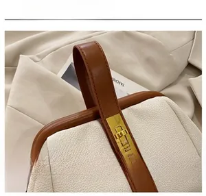 Detail of cream lychee leather shell bag with gold clasp and brown handle