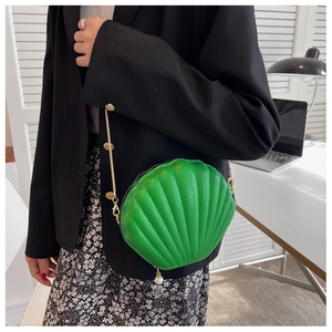 Detail view of green shell-shaped crossbody bag with gold chain and pearl pendant