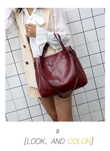 Detalle del bolso tote rojo vino en cuero encerado con textura suave y asas alargadas