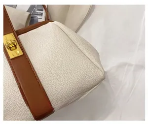 Close-up of pebble leather texture with gold metal buckle on a beige and brown bag