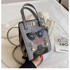 Detail of grey crocodile pattern handbag with cartoon character and pearl accessories
