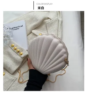 Detailed close-up of cream-white shell-shaped crossbody bag with gold chain and litchi texture
