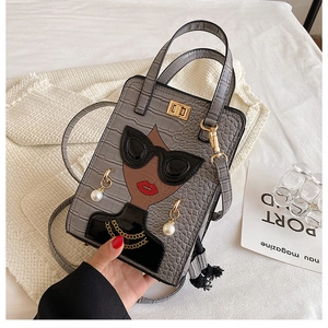 Detail of grey crocodile texture handbag featuring a 3D pop art girl with pearl earrings