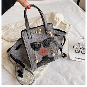 Detail of grey crocodile texture bag with stylish female motif and gold turn-lock