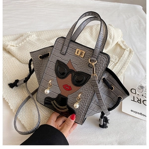 Detail of grey crocodile pattern handbag featuring a 3D fashion girl design and pearl charm