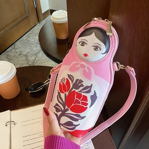 Pink Russian doll PU leather crossbody bag with floral patterns held in a cafe setting