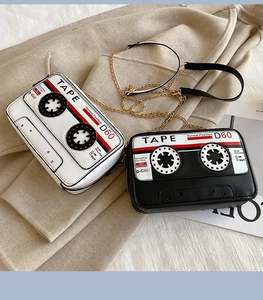 Close-up of retro cassette tape shaped shoulder bags in black and white with gold chains