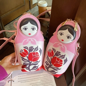Creative 3D Matryoshka doll crossbody bag in pink with floral print on wooden table