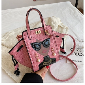 Detail of pink croc-embossed wing bag featuring cartoon woman portrait and pearl earring charm