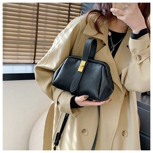 Detail of black lychee grain leather shell bag with golden twist lock and top handle