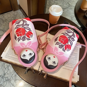 Close-up of pink Russian nesting doll crossbody bag with floral prints and gold zippers