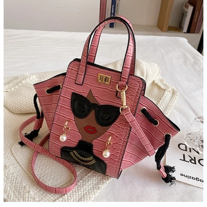 Detail view of pink crocodile-embossed handbag with cartoon girl and pearl charm