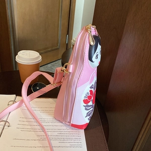Pink Russian doll crossbody bag displayed on a coffee table with books and sunglasses